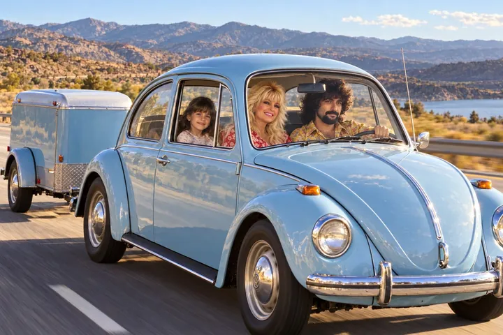 Sandra, Gino and a young girl driving a light blue Volkswagen Beetle with a trailer through the California hills
