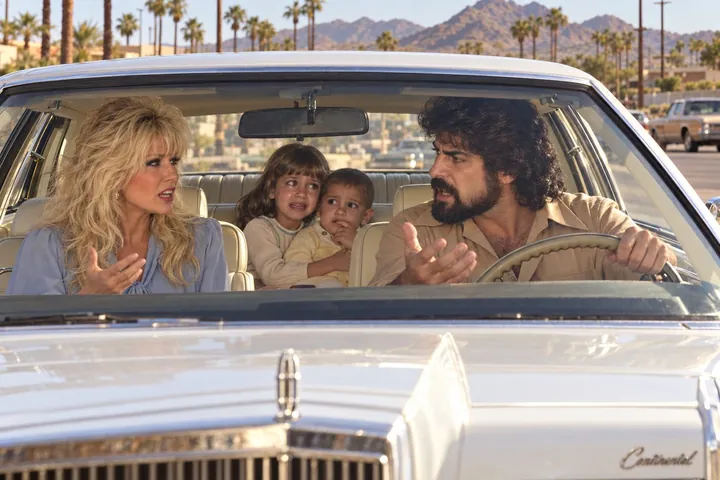 Sandra and Gino arguing in the front of a white Lincoln Continental while two frightened children huddle in the back seat